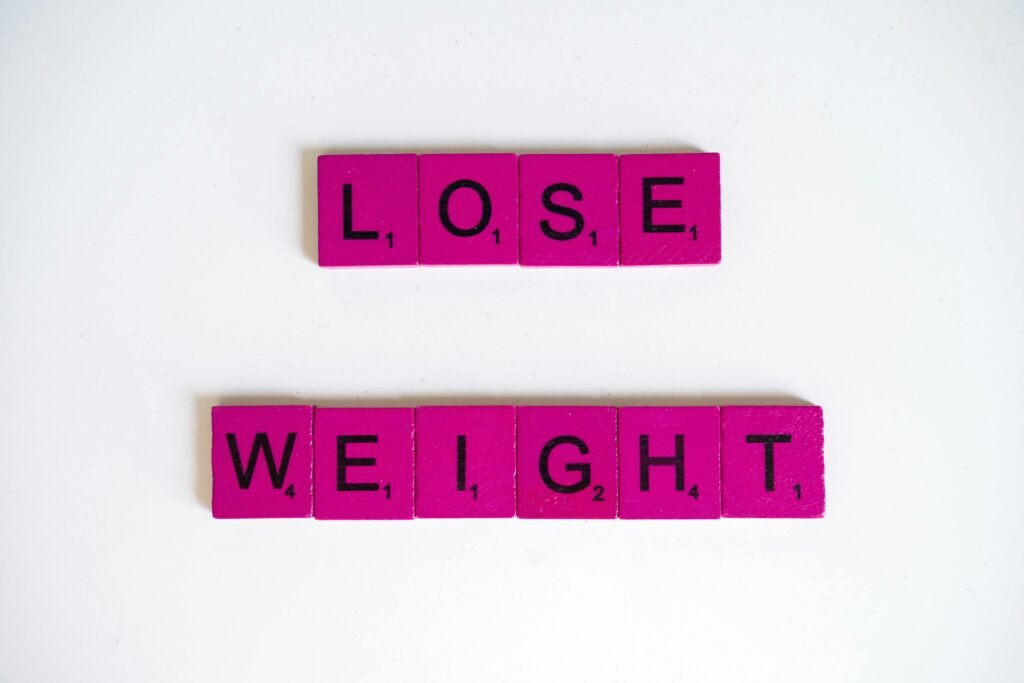 Creative image of the phrase 'Lose Weight' spelled with Scrabble tiles on a white background.